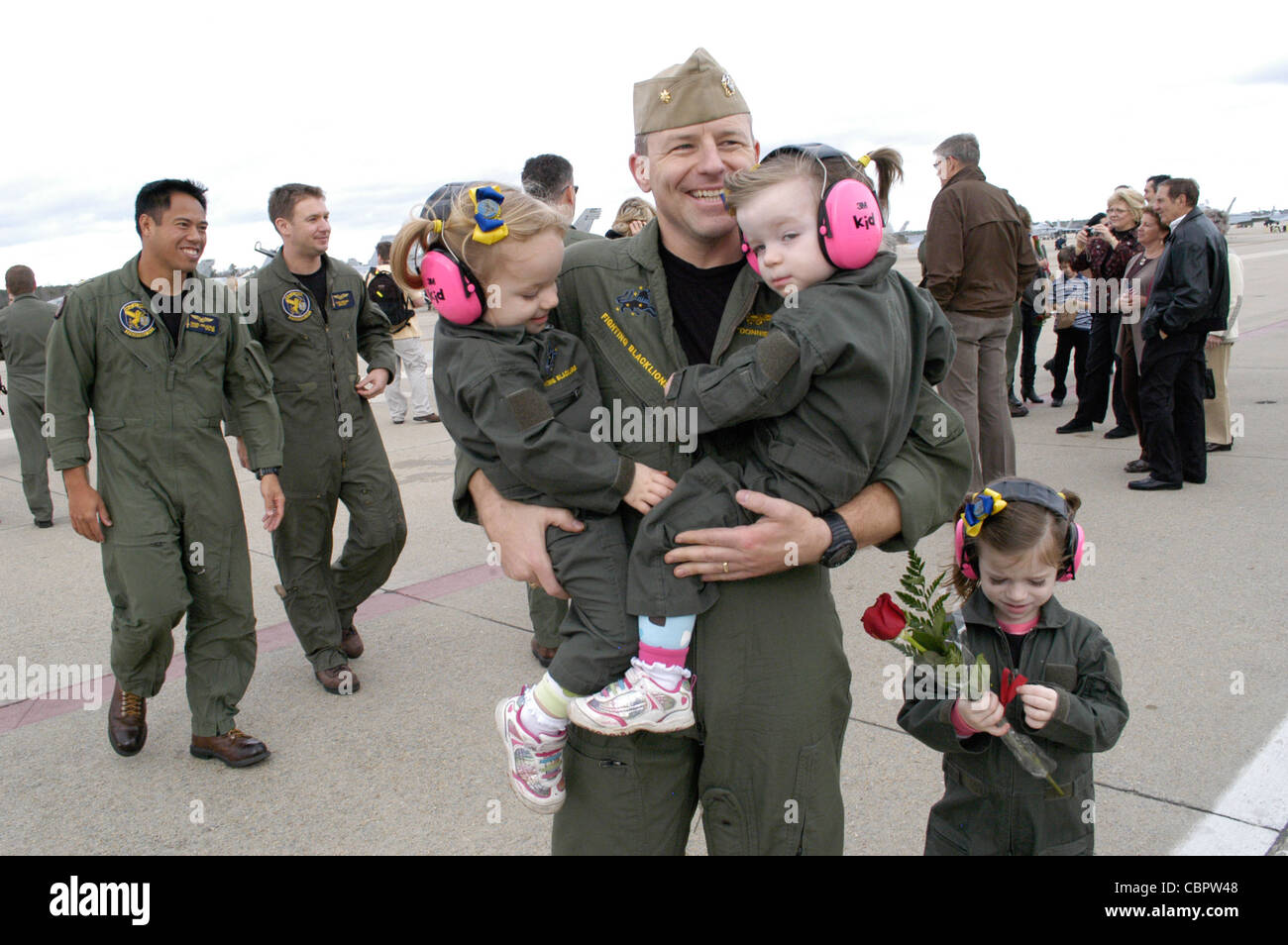 NAVAL AIR STATION OCEANA (Dec. 07, 2011) Lt. Cmdr. Joseph Greenslade, assigned to Strike Fighter Squadron (VFA) 213, hugs his twin daughters after the squadron returned from six-month deployment aboard USS George H.W. Bush (CVN 77). Stock Photo