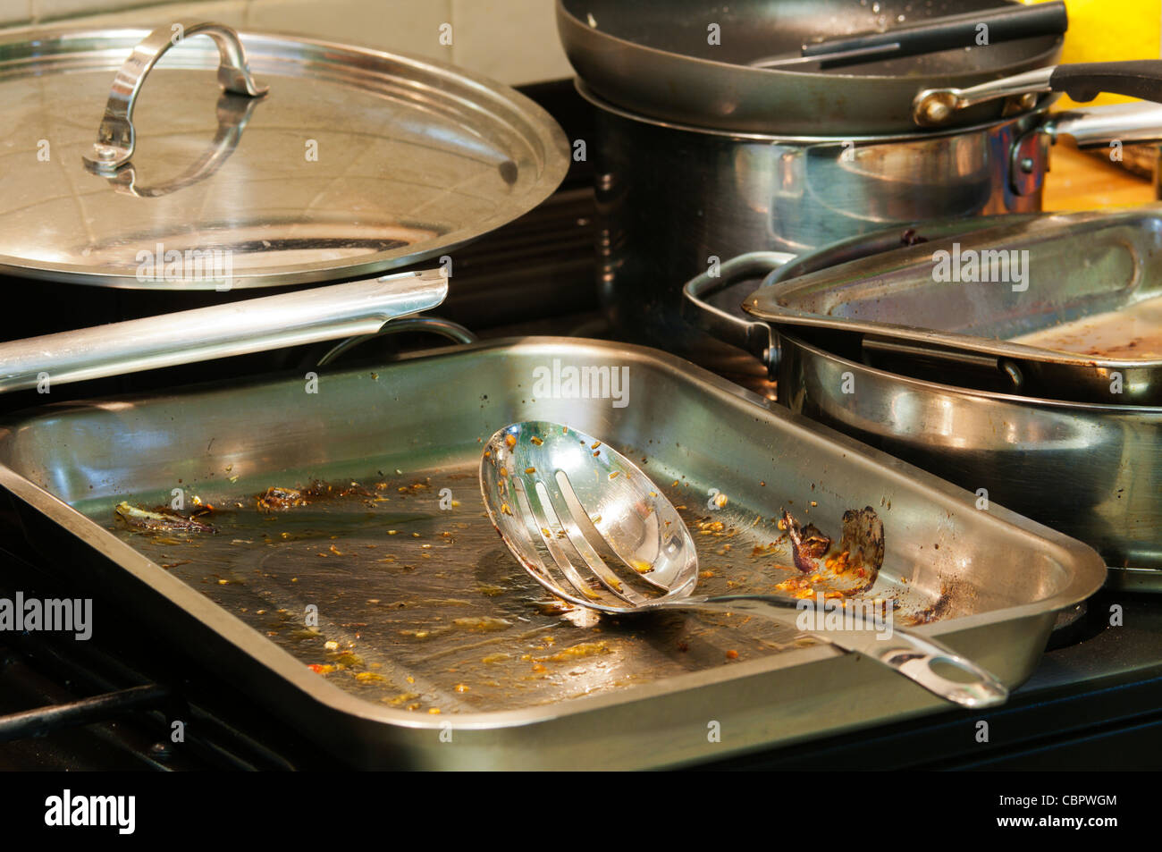 A selection of roasting tins, saucepans and frying pans in a kitchen waiting to be washed up. Stock Photo