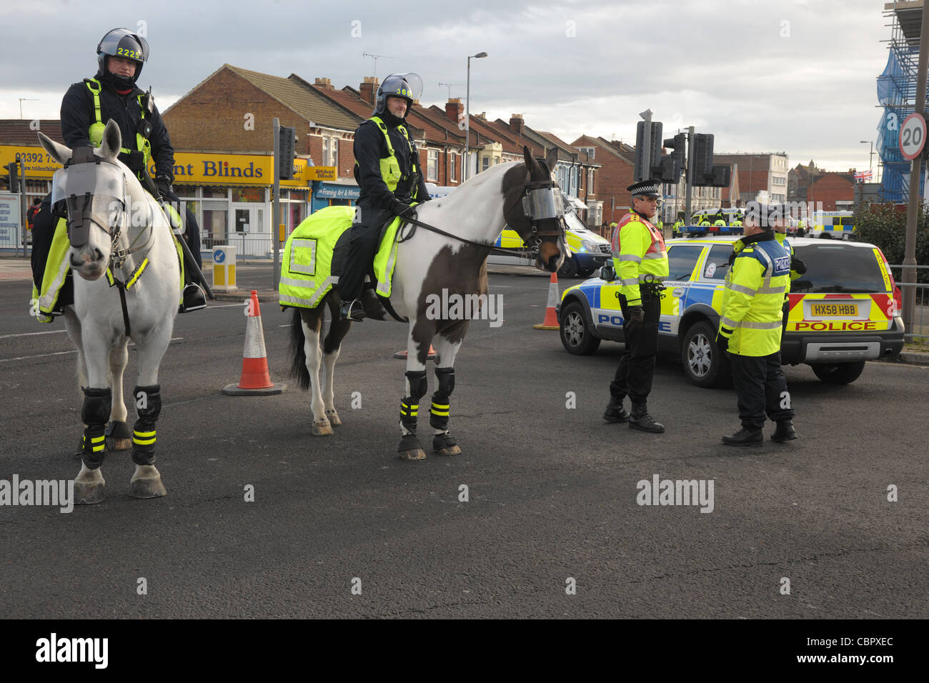 Mounted officers and foot police block a major road junction during a football match crowd control. Portsmouth Hampshire. Stock Photo