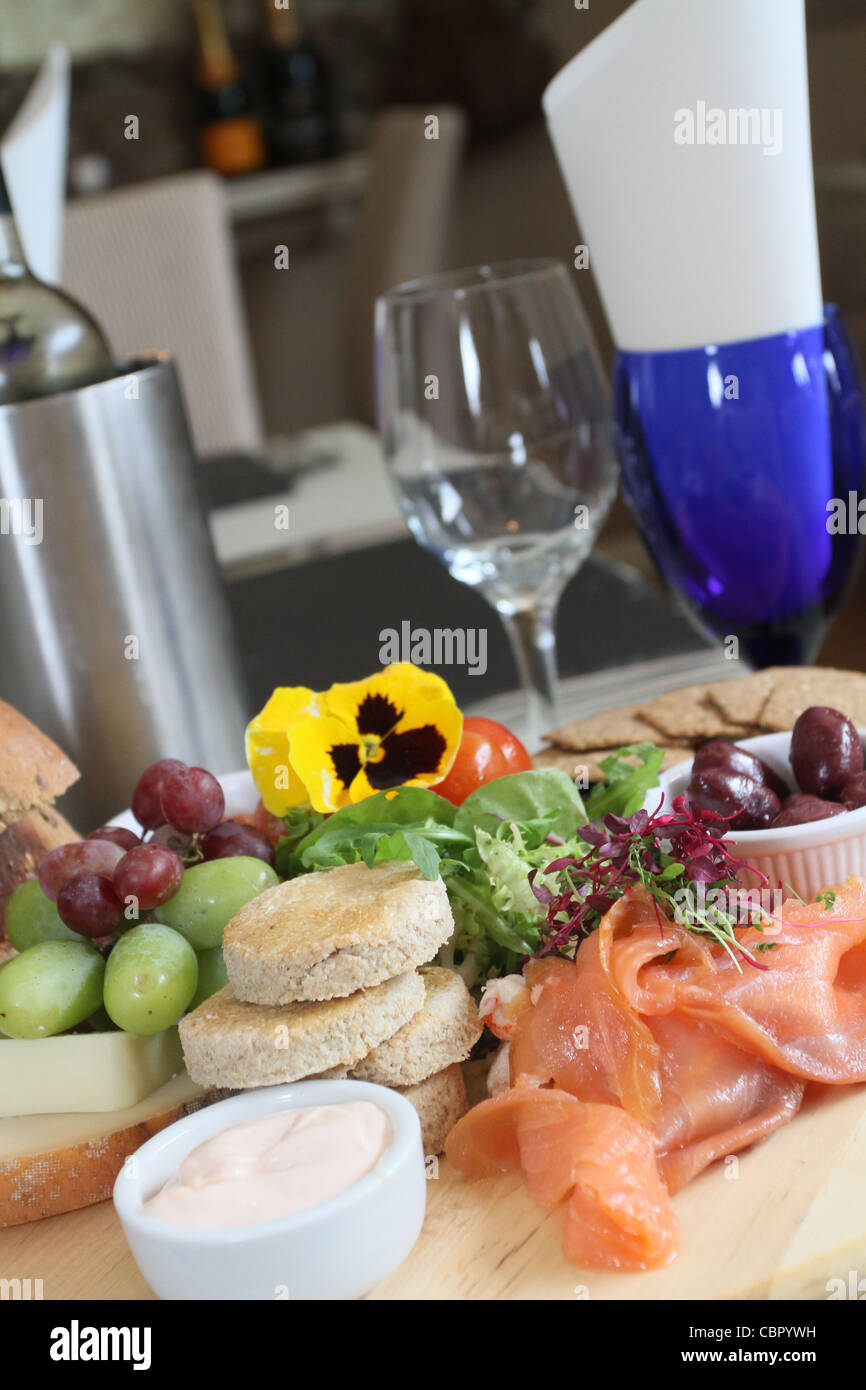 Smoked Salmon with black olives, grapes & salad in a restaurant setting Stock Photo