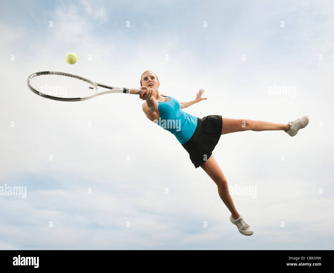 Caucasian woman jumping in mid-air playing tennis Stock Photo