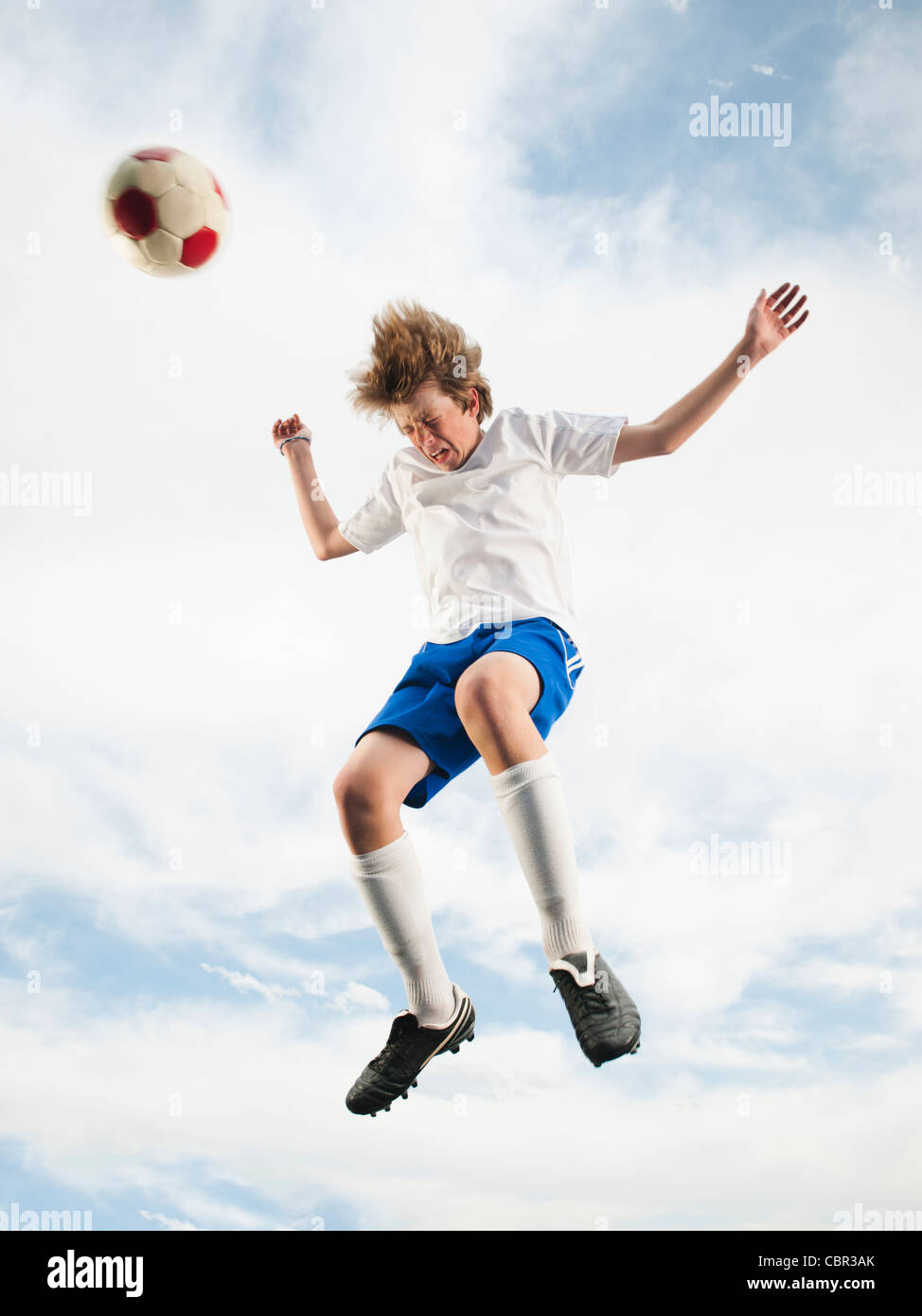 Caucasian teenager heading soccer ball in mid-air Stock Photo