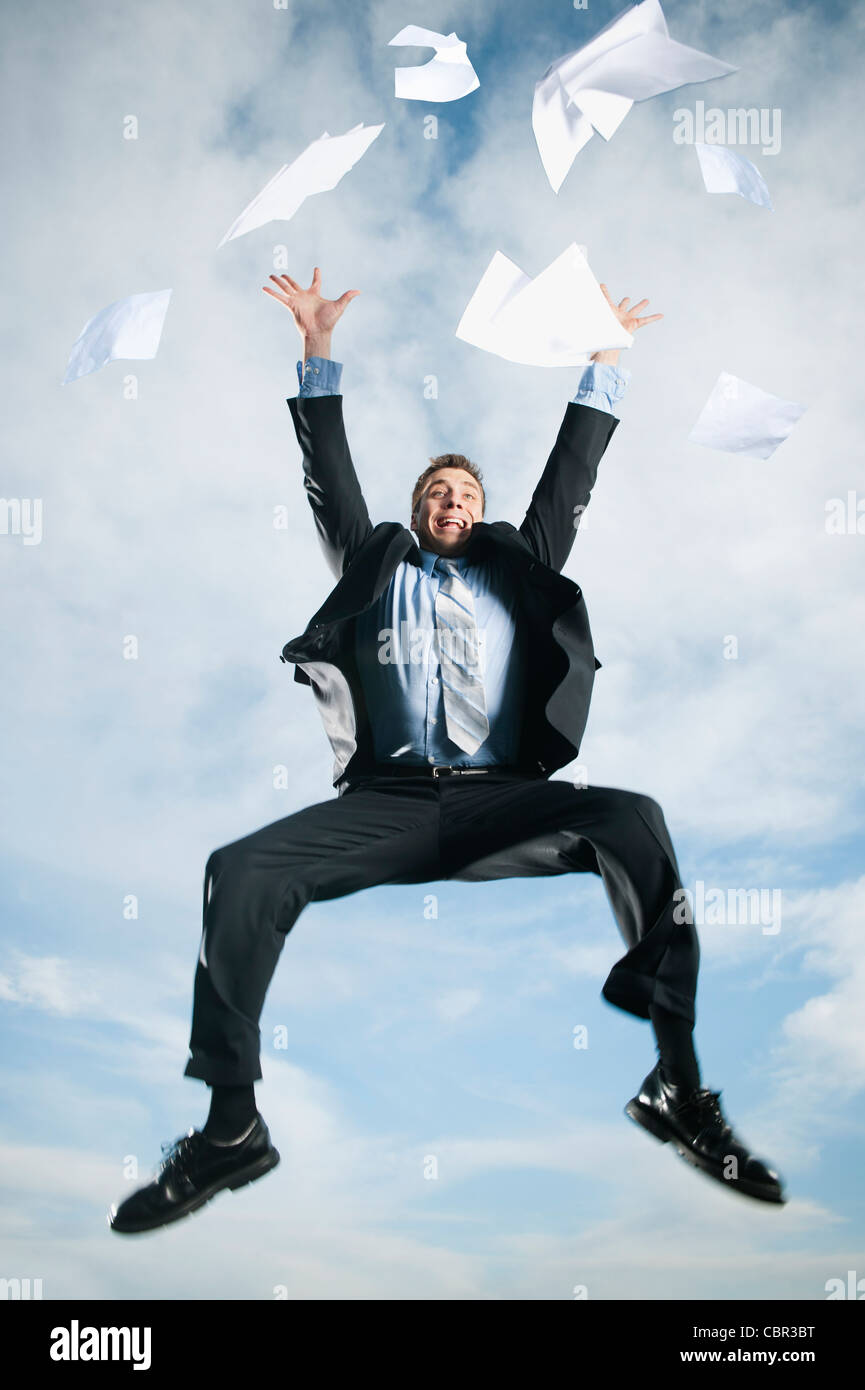 Caucasian businessman jumping in air scattering papers Stock Photo