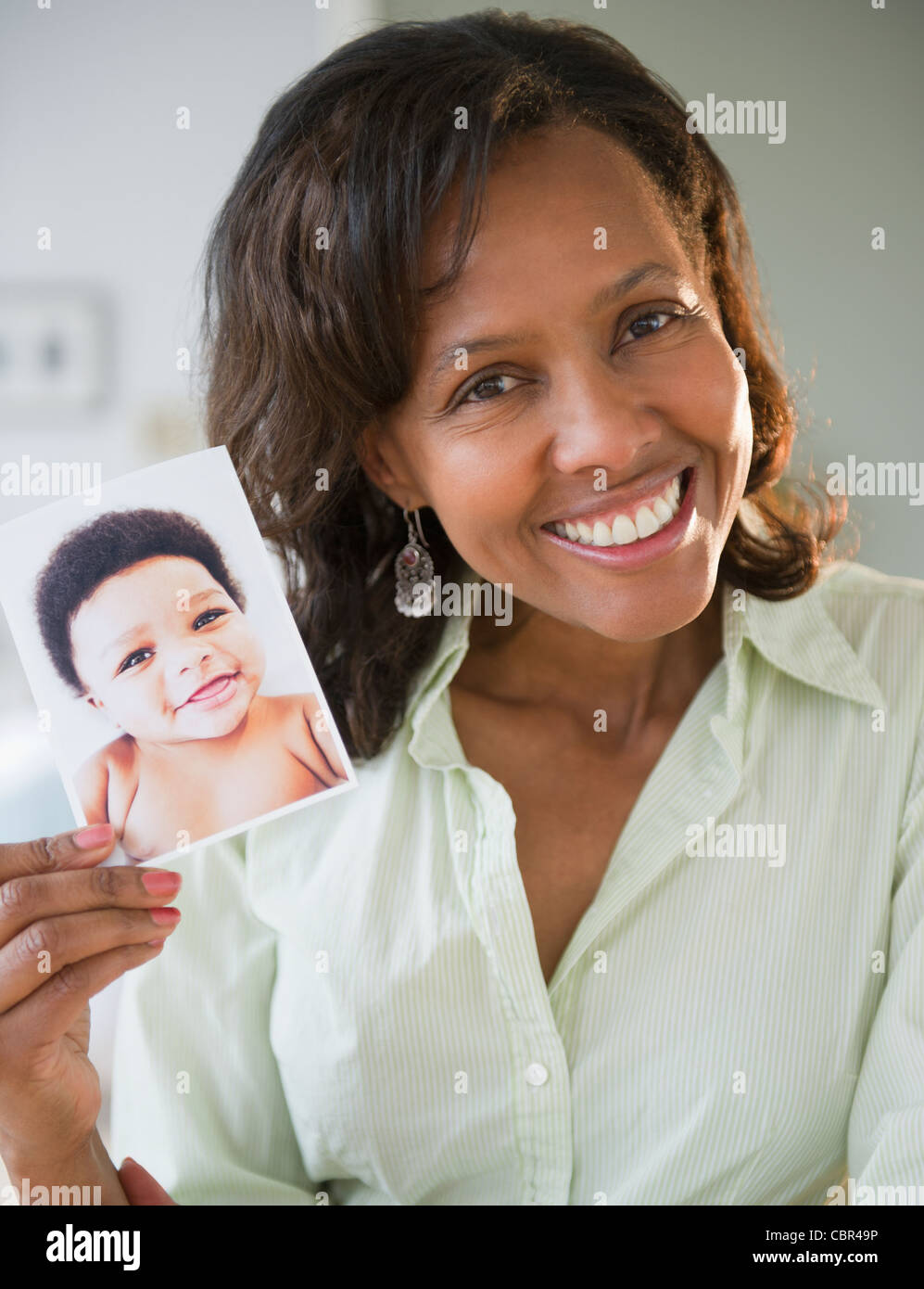 Black woman holding photograph of baby Stock Photo