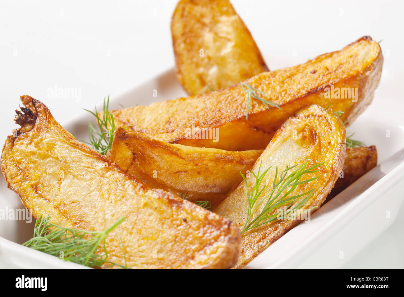 Roasted potato wedges garnished with fresh dill Stock Photo