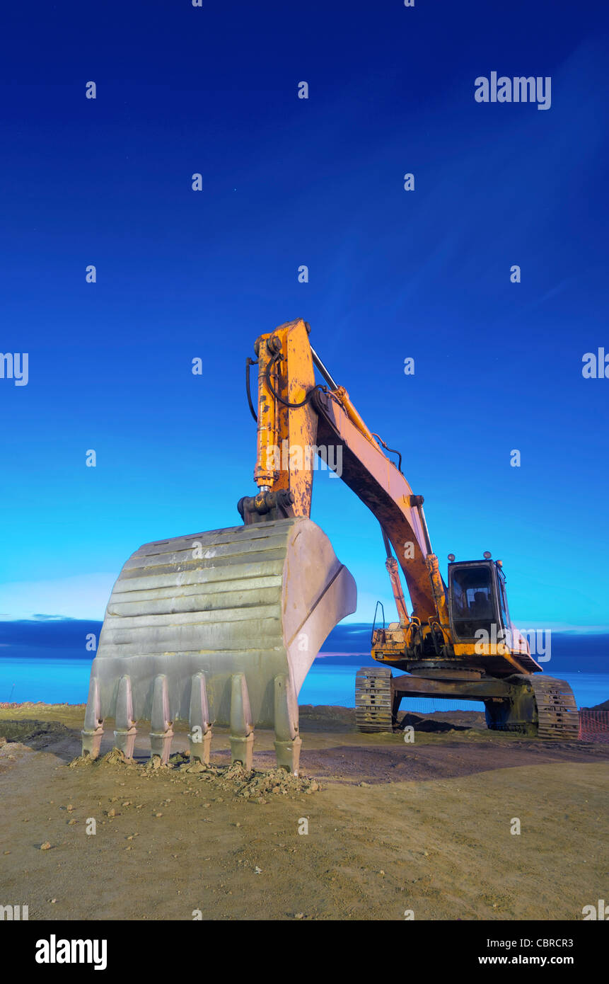 view of a yellow backhoe on a beach at sunrise Stock Photo - Alamy