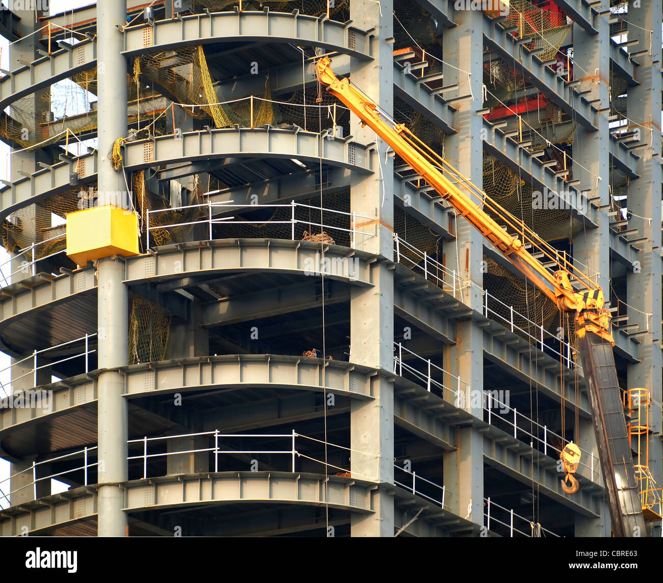 A large scale construction site of an office tower with steel bars and girders and a yellow