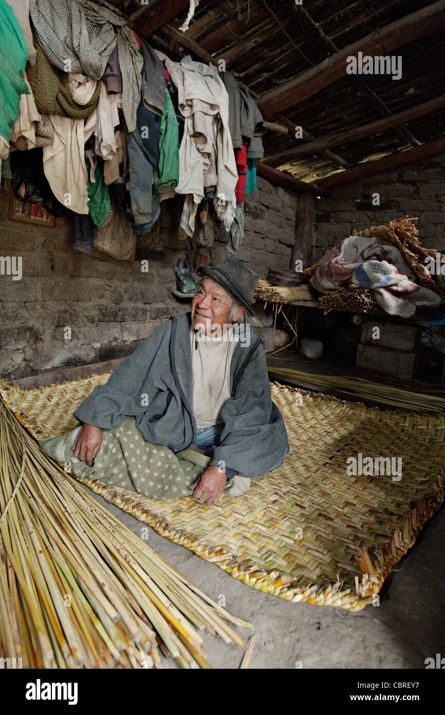 Man weaving a traditional straw carpet in a village near Otavalo, Ecuador. Stock Photo