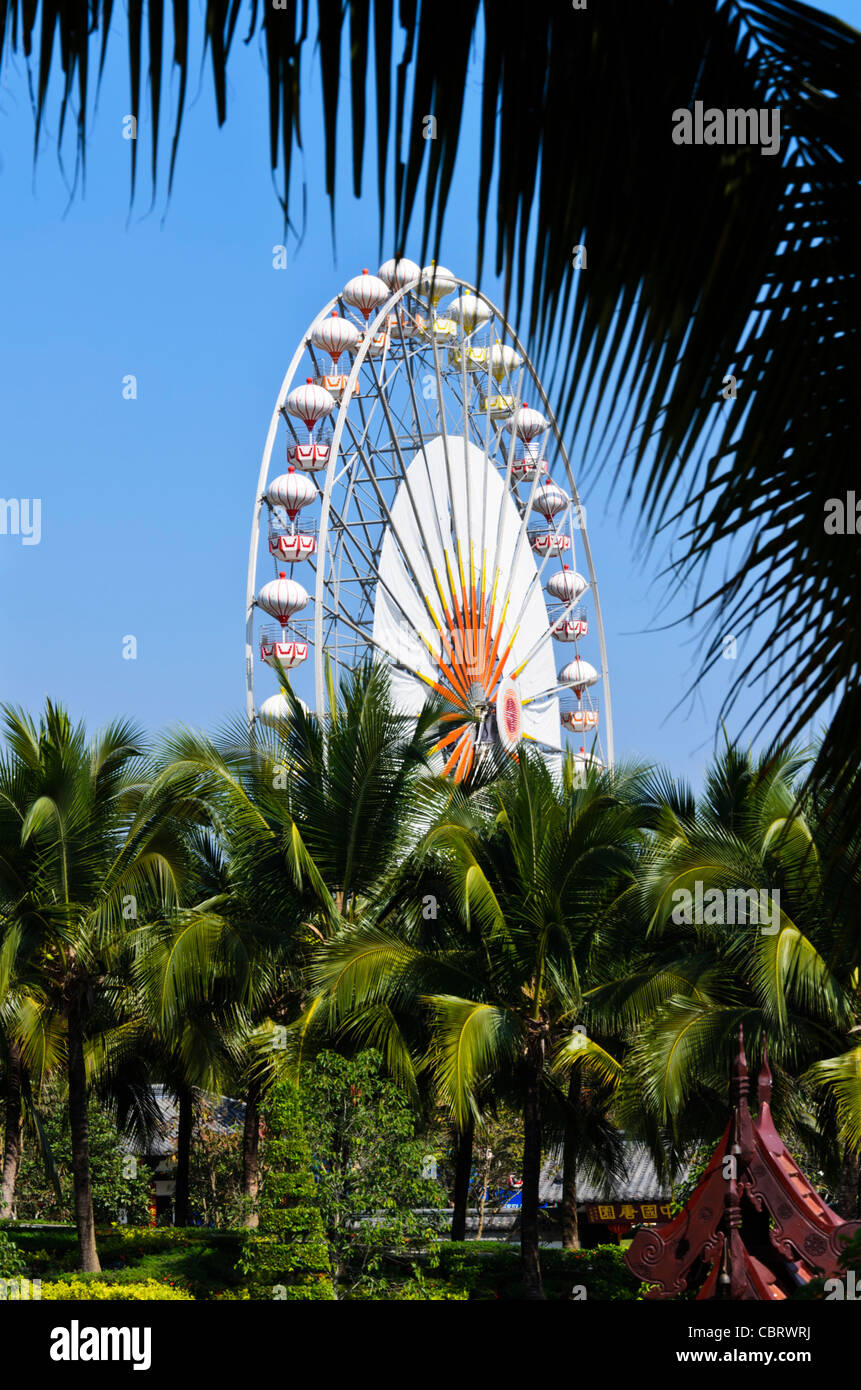 Huge Ferris wheel in clear blue sky above coconut palm trees at Royal Flora Ratchaphruek in Chiang Mai Thailand Stock Photo