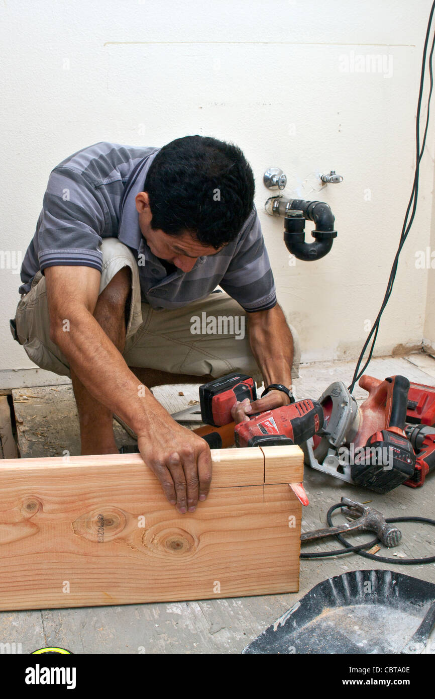 Hispanic man from Mexico working his own construction business in the USA replaces support beam in upstairs bathroom USA. MR © Stock Photo