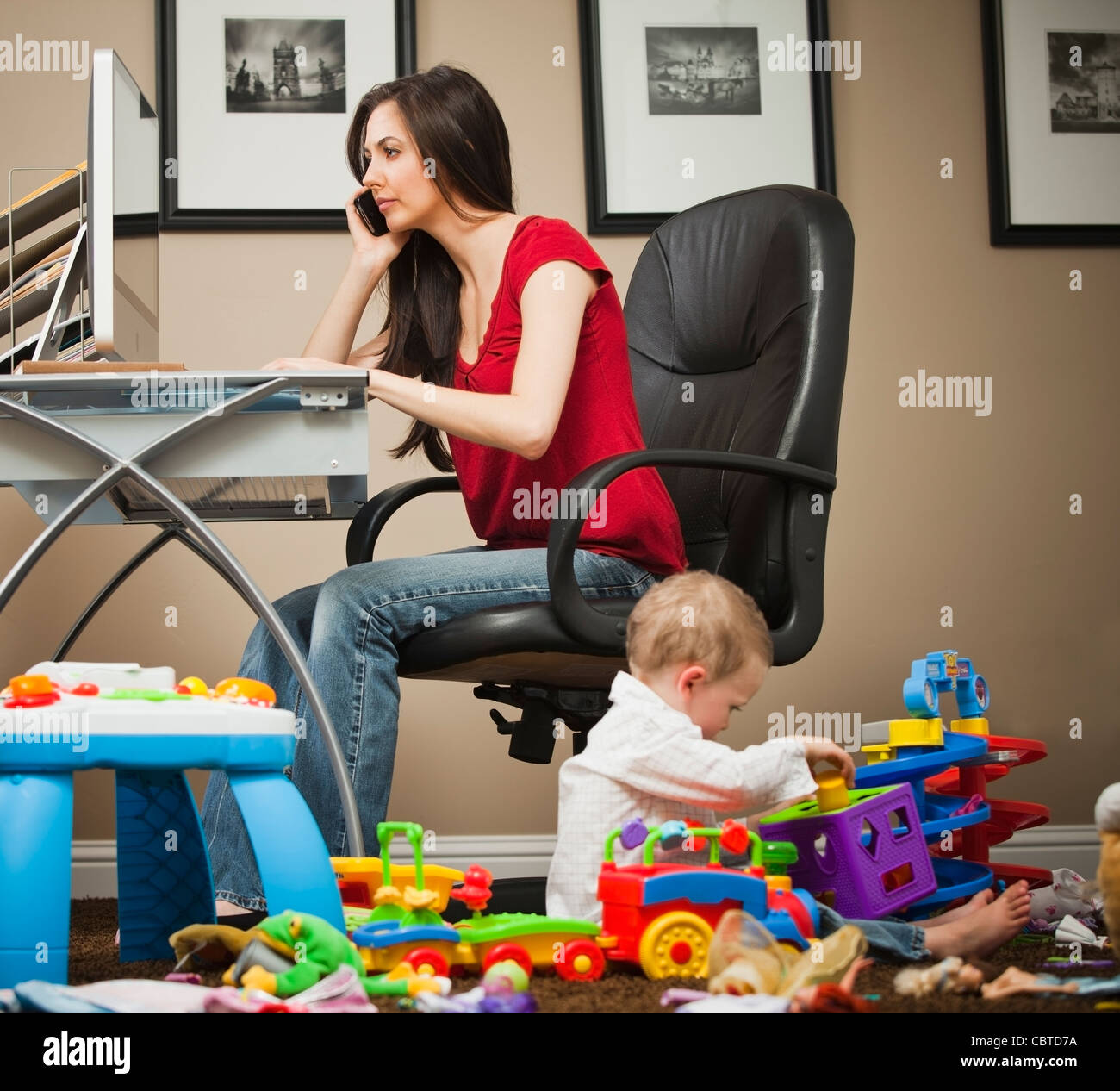 Caucasian woman tending child and working in home office Stock Photo