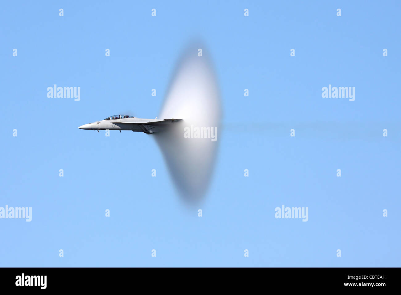 Vapor cone covers the tail of an F/A-18 Hornet during a high speed pass Stock Photo