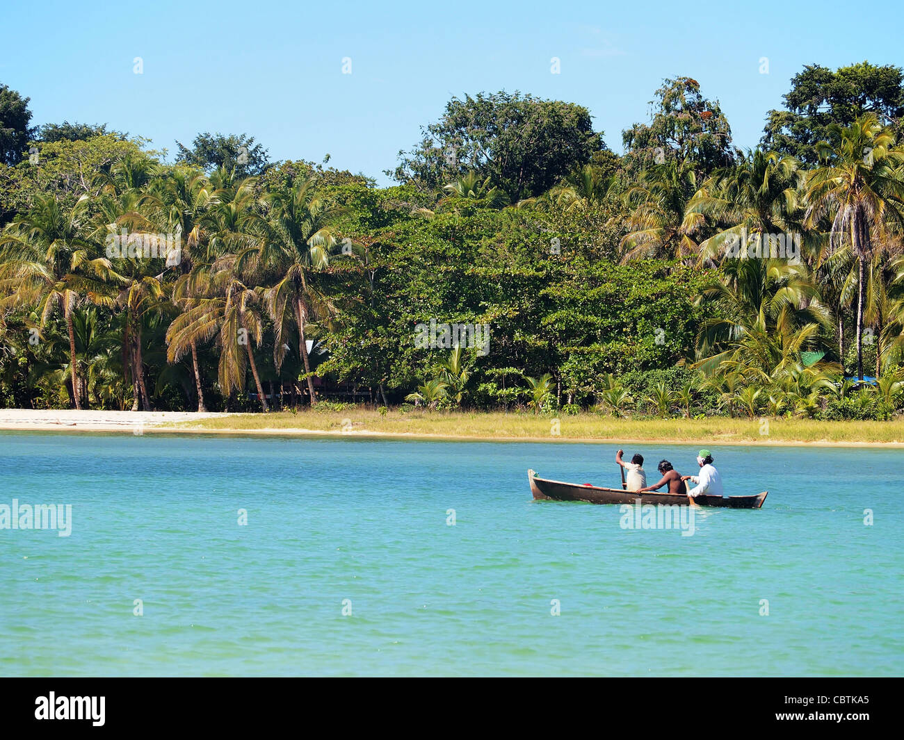 Dugout canoe with amerindian people near a beach in Bocas del Toro, caribbean sea, Panama Stock Photo