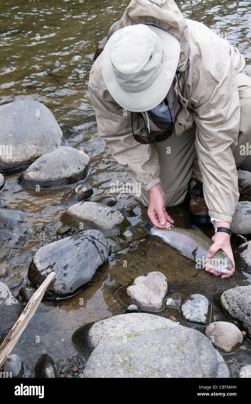 An angler admires his big trout caught in a small New Zealand river in