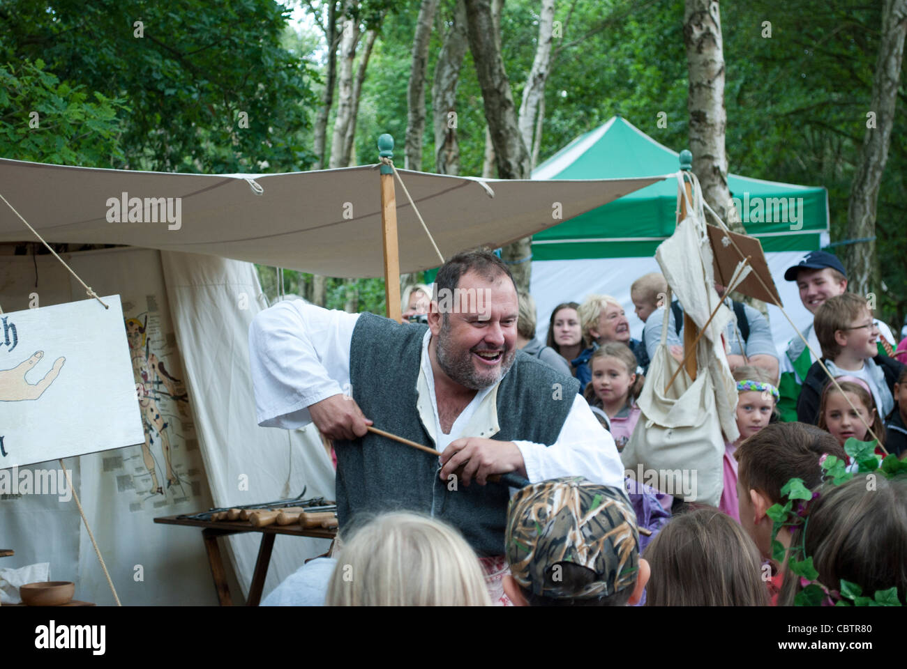 Man dressed as medieval  surgeon gives demonstration of old medical practices in front of a crowd of children Stock Photo