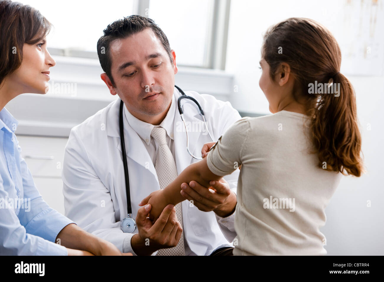 Doctor examining patient while mother watches Stock Photo
