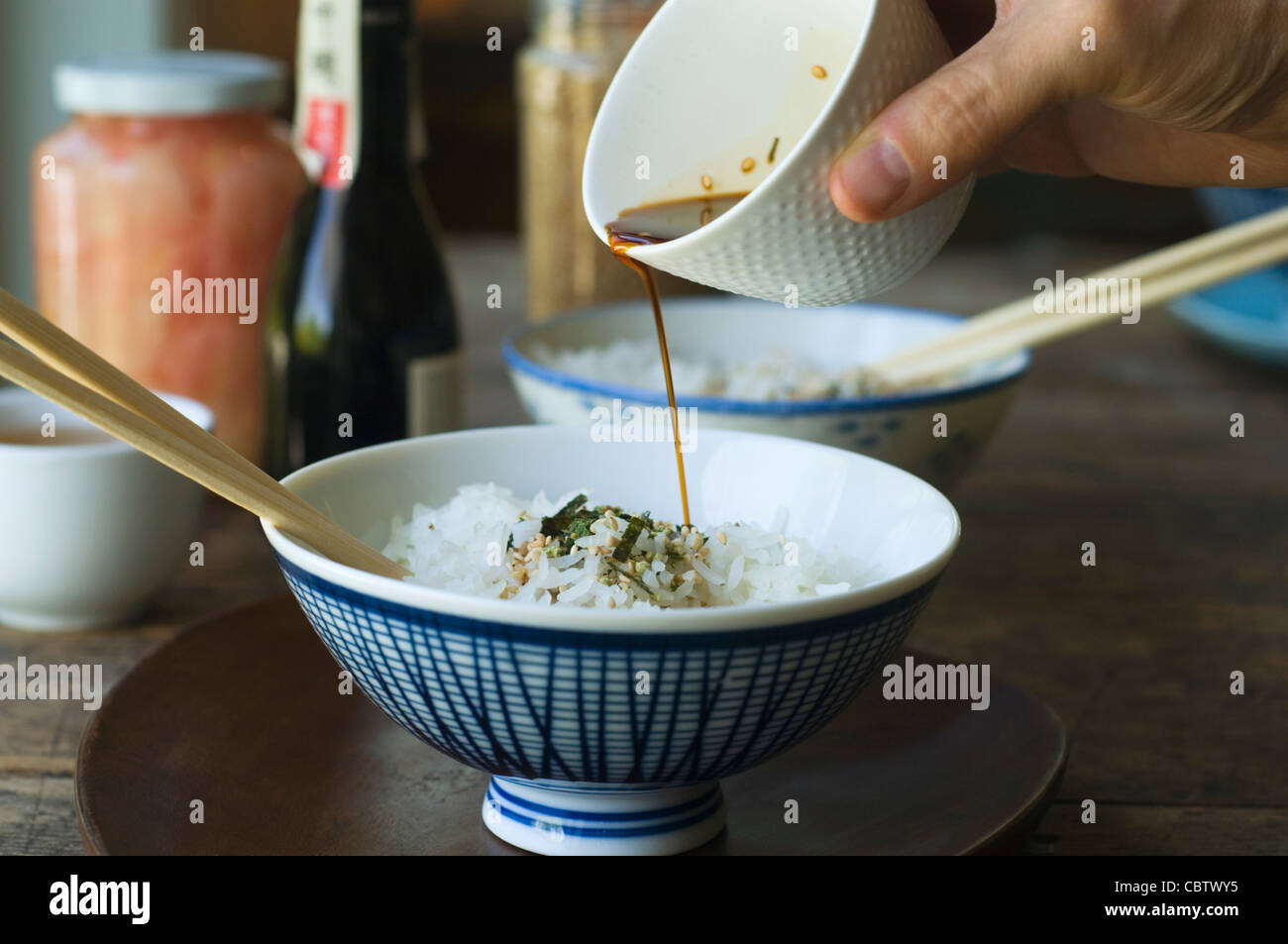 Person pouring sauce over bowl of rice Stock Photo