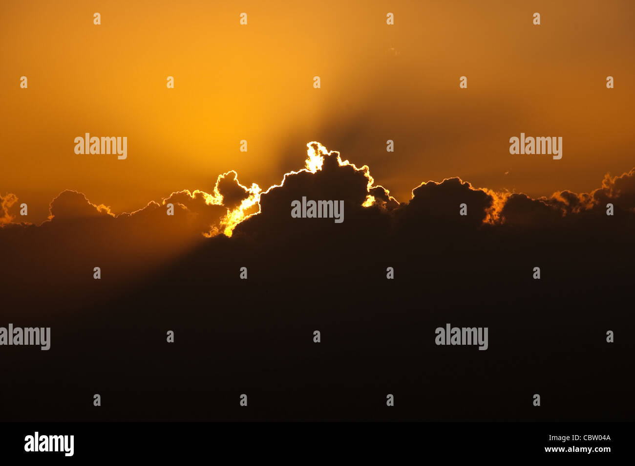 sun setting behind big cloud creating orange glow in the sky Stock ...
