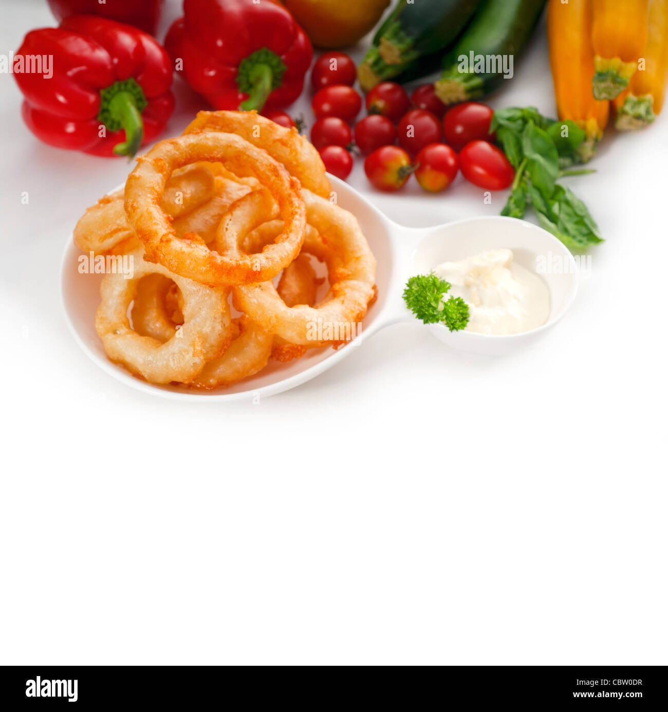 golden deep fried onion rings served with mayonnaise dip and fresh vegetables oln background