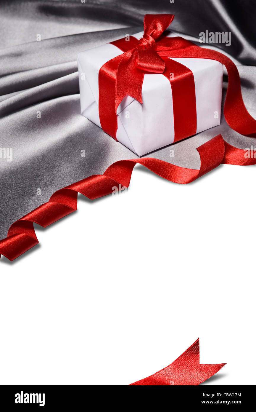 christmas gift with red ribbon, on silver satin material Stock Photo
