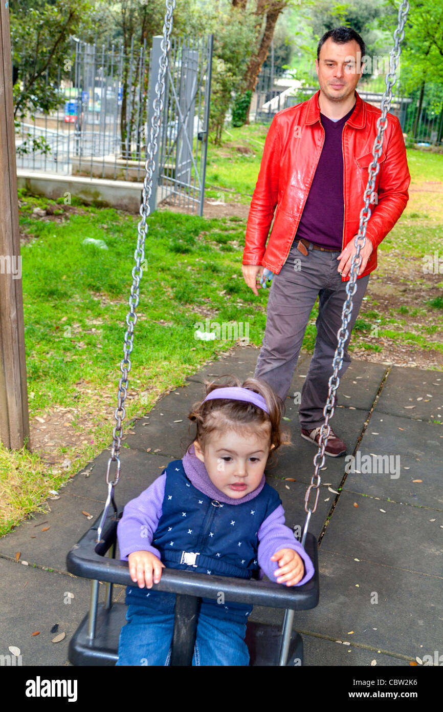 Father pushing daughter on a swing Stock Photo
