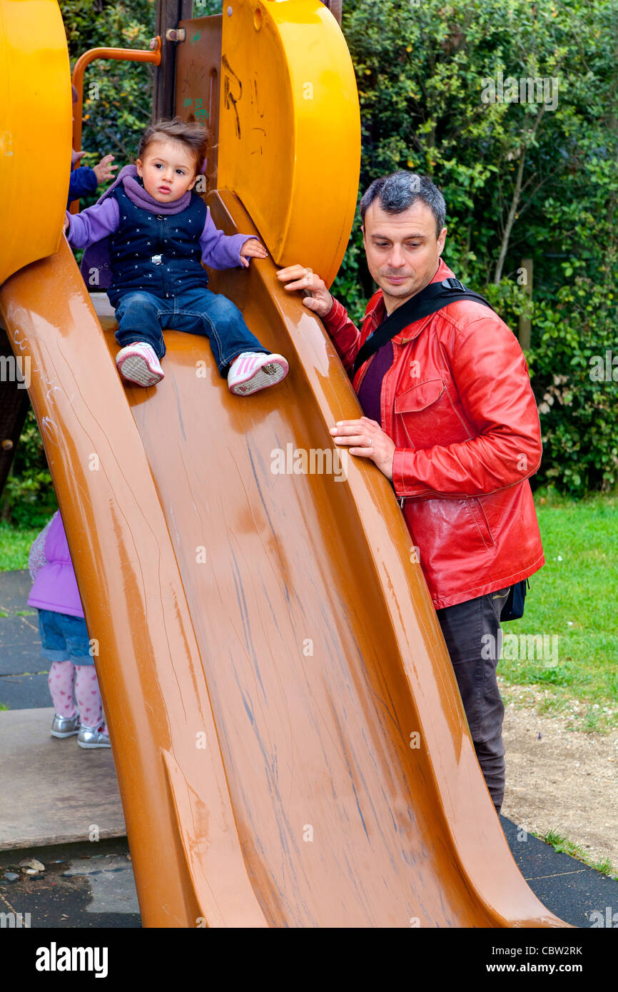 Father and daughter on a playground slide Stock Photo