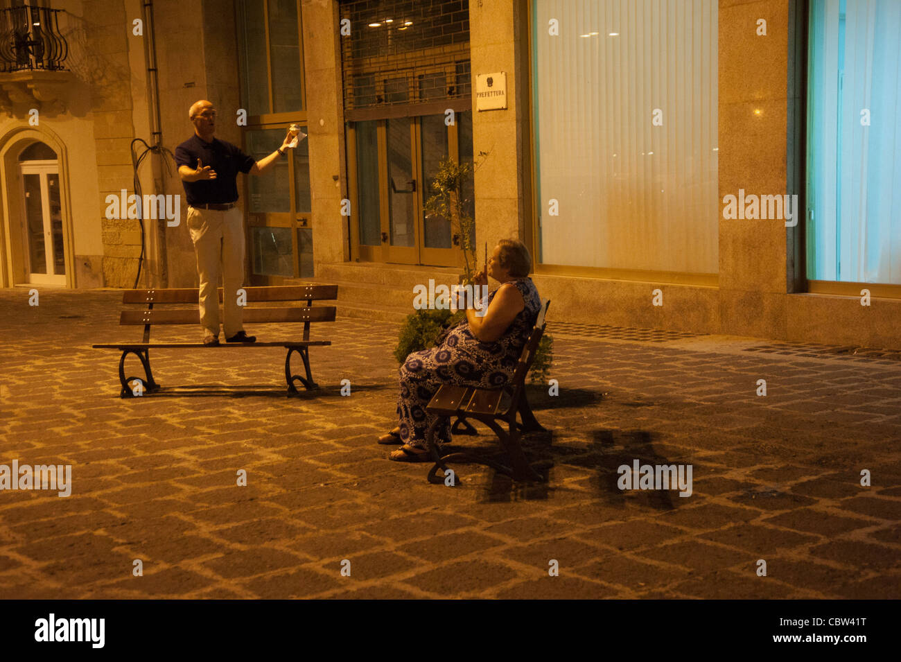 Husband brings a serenade to his wife at night at square in Syracusa, Sicily, Italy, funny, romantic Stock Photo