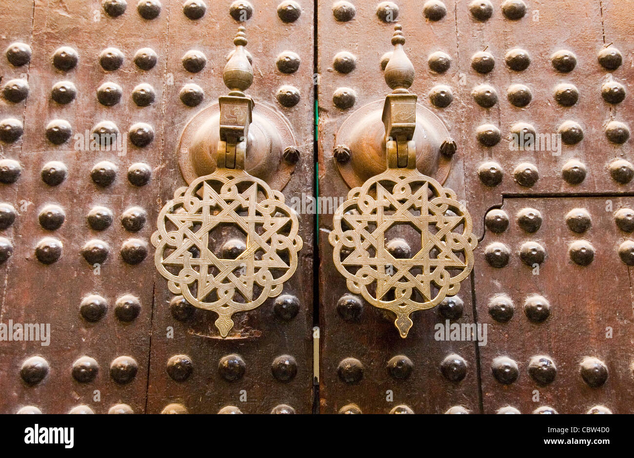 Brass door knocker handles on a heavy wooden door in the medina of Fez