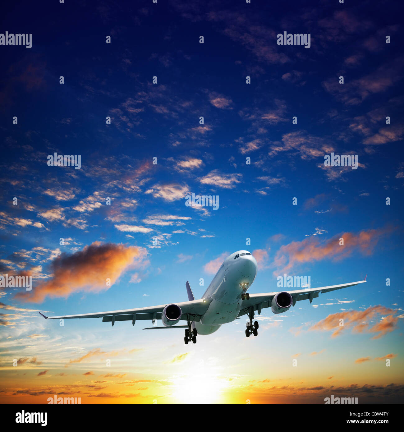 Jet airplane in a sky at sunset time. Square composition. Stock Photo