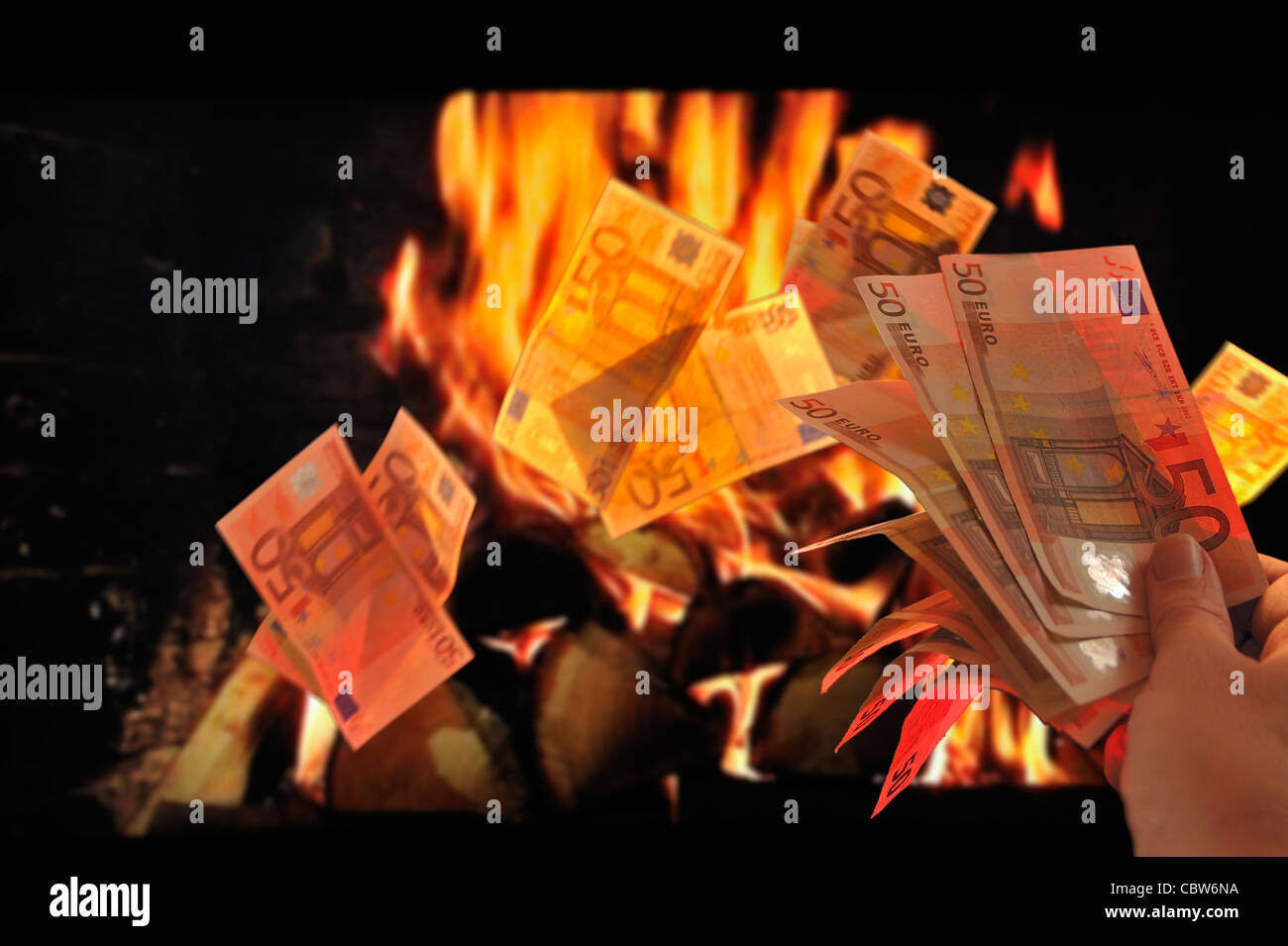 Burning European money by throwing euro bank notes in flames of fireplace to symbolize recession and crisis in the Europe zone Stock Photo