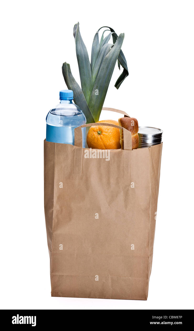 Fresh groceries in a brown bag. Including bread, orange, water, can and leek Stock Photo