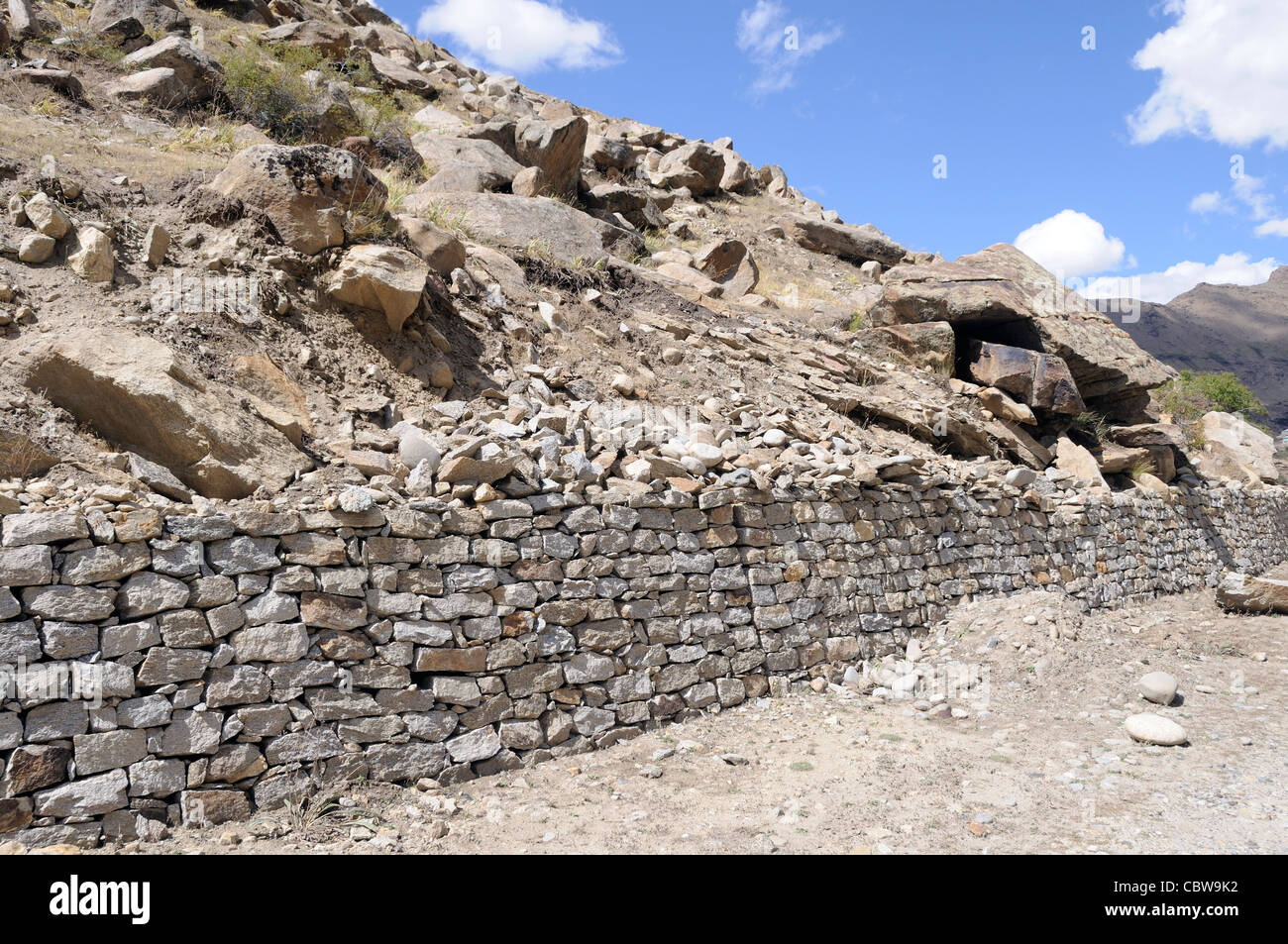 A dry stone wall made of dressed stone holds back the mountainside above the road to Rangdum. Zanscar, Ladakh, India Stock Photo