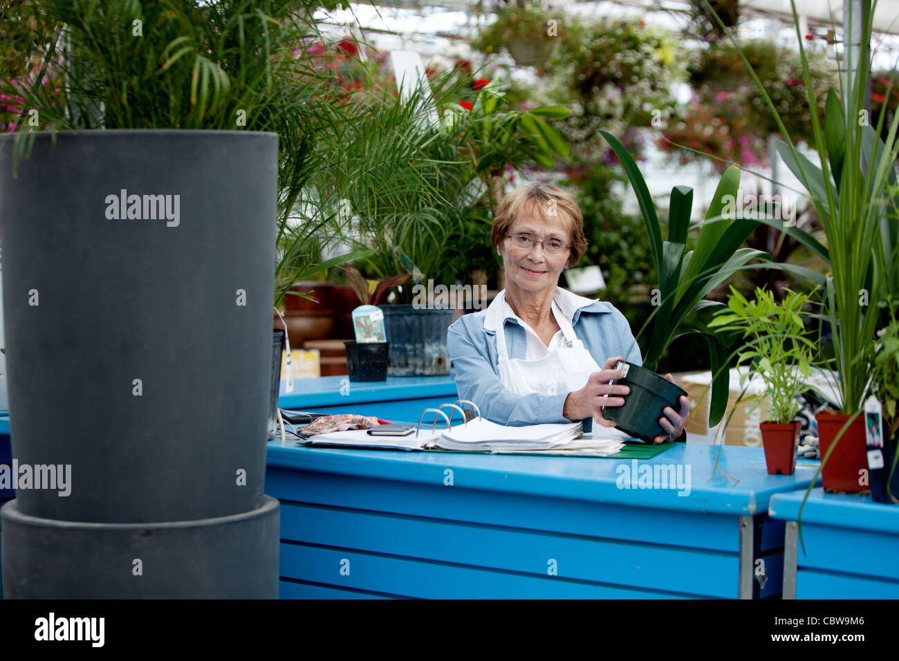 Portrait of a senior woman working in a garden center Stock Photo - Alamy