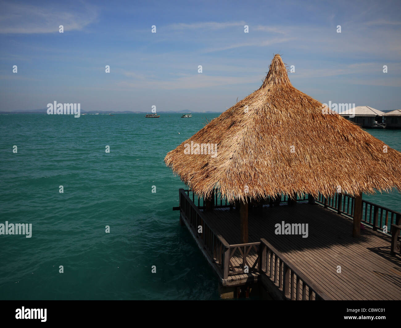 Tropical straw hut stretched out onto Blue Ocean Stock Photo