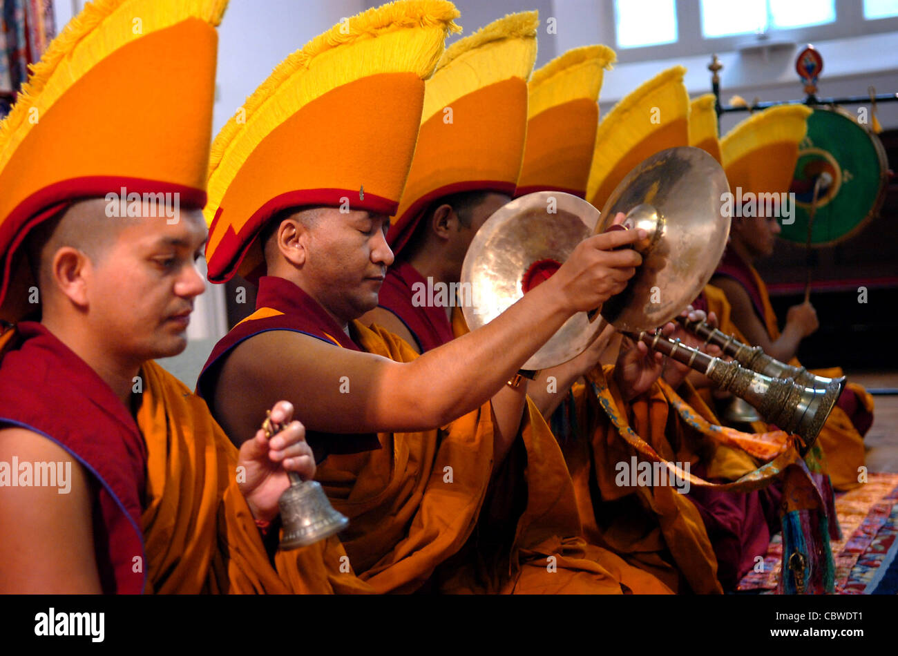 Tibetan monks chant and play musical instruments before they begin to create a Chenrezig Sand Mandala in Brighton UK Stock Photo