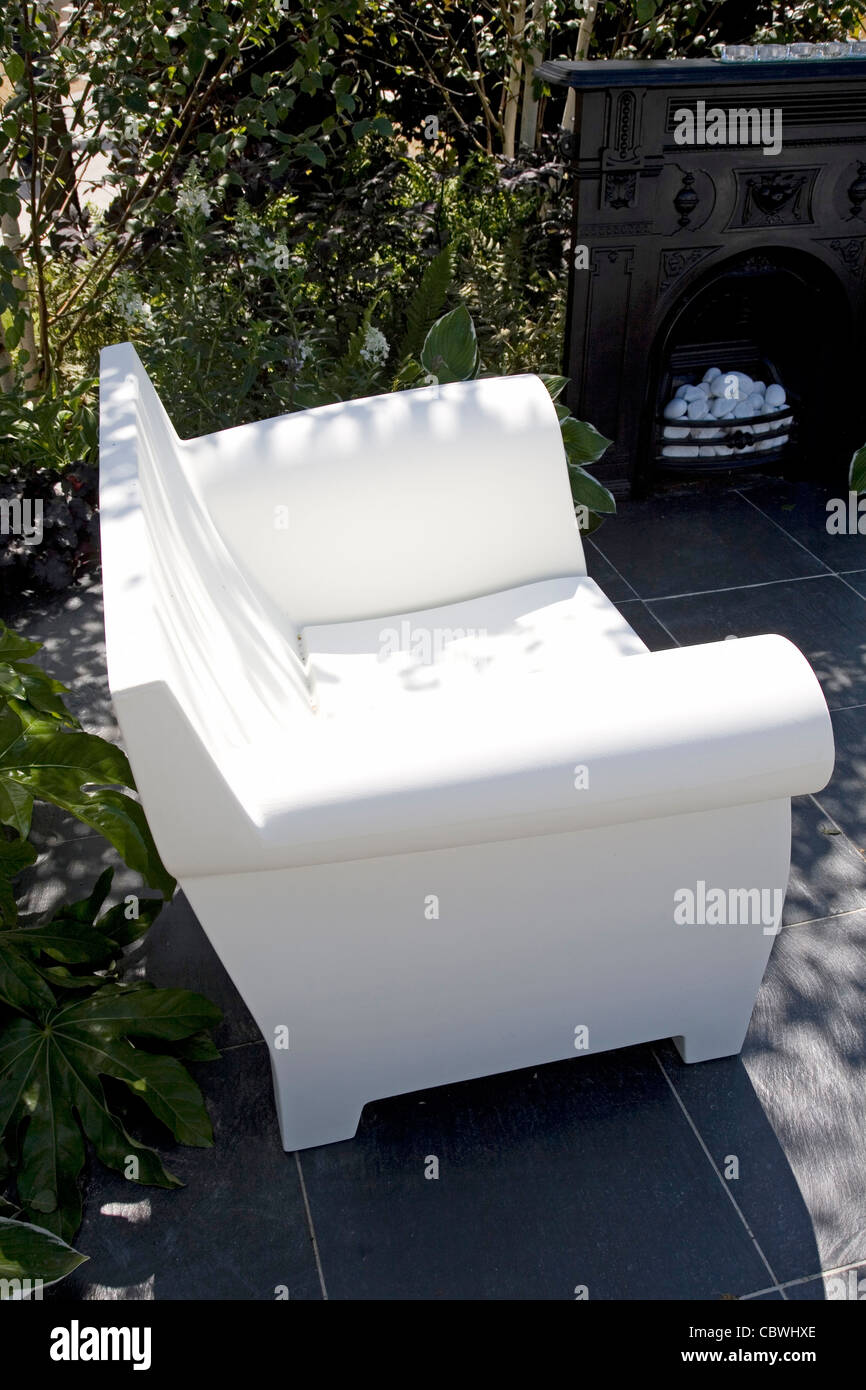 Contemporary garden seat in a black and white themed garden. Oversized armchair made from white acrylic. Stock Photo