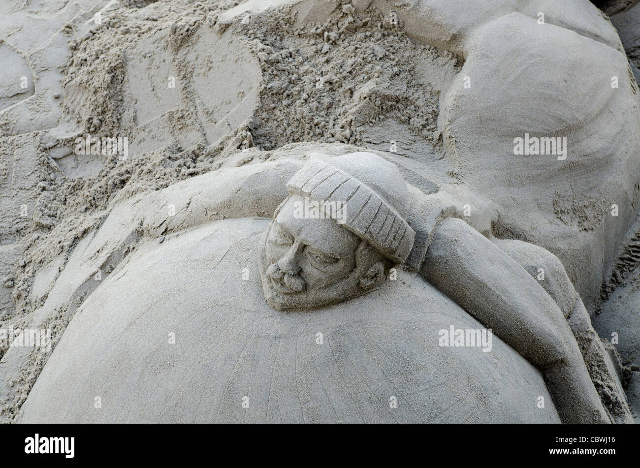 Sand sculpture carving of head  Shore South bank of river Thames London Uk Stock Photo