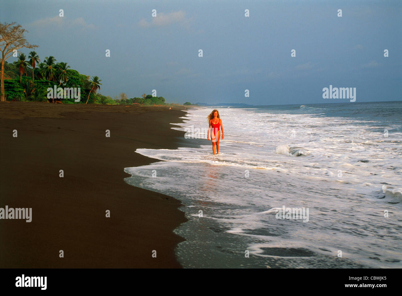 Woman on black lava sand beach at Playa Hermosa in Costa Rica Stock Photo