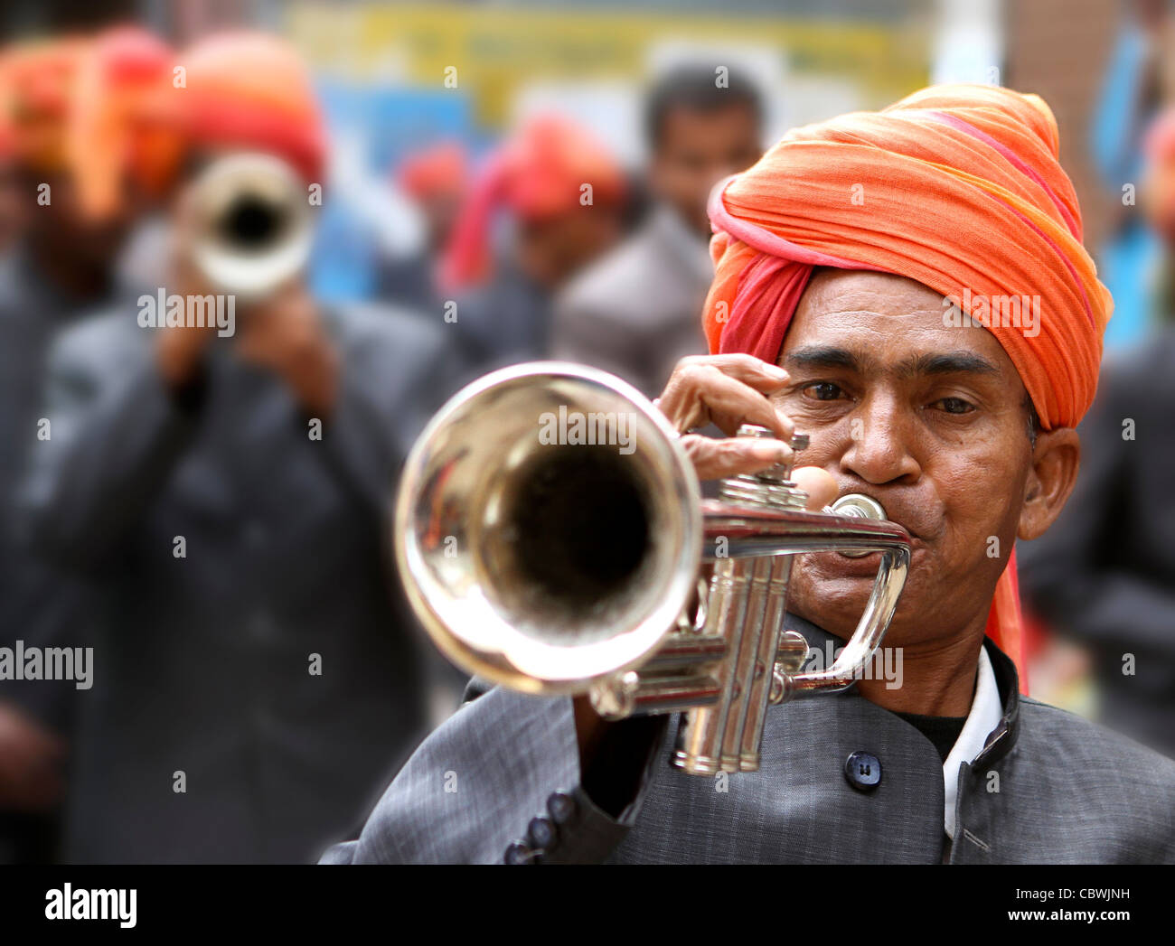 Indian man with orange turban playing trumpet at a street festival. Pushkar. Rajasthan. India Stock Photo