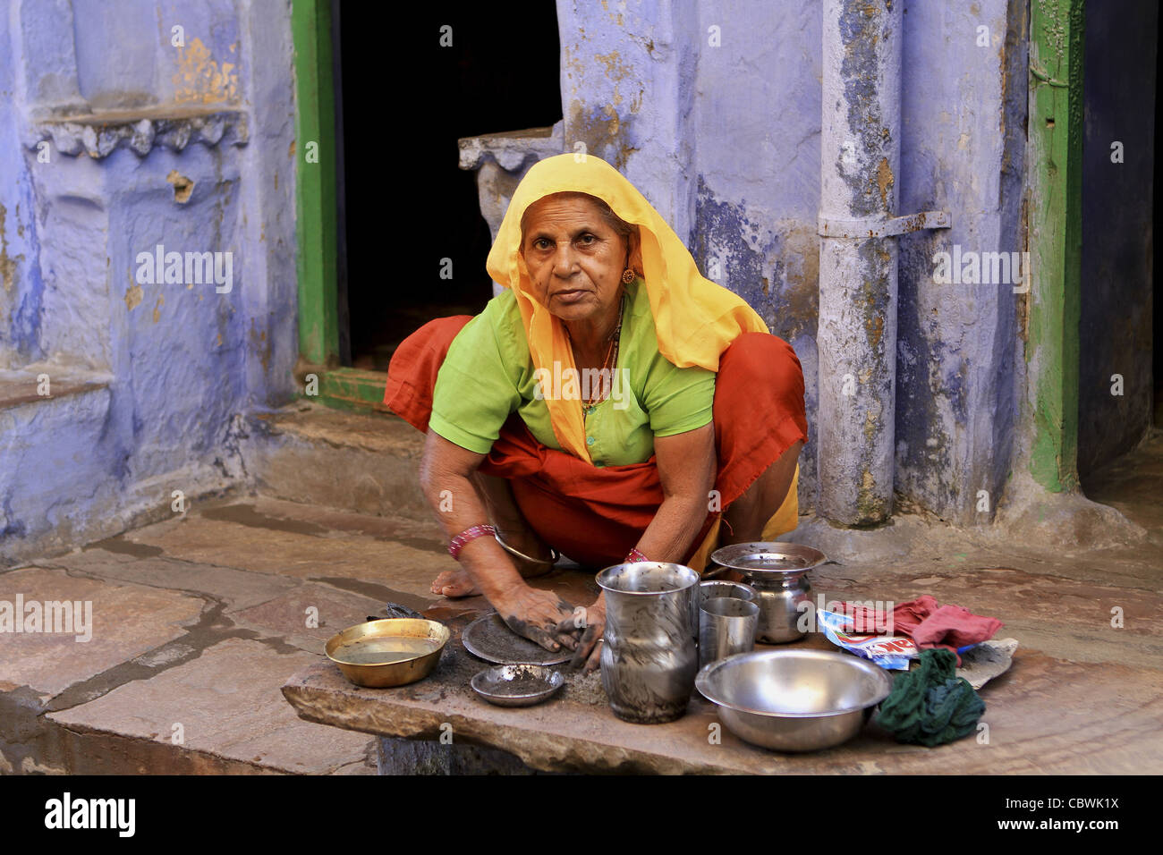 Woman washing dishes on doorstep. Bundi. Rajasthan. India Stock Photo