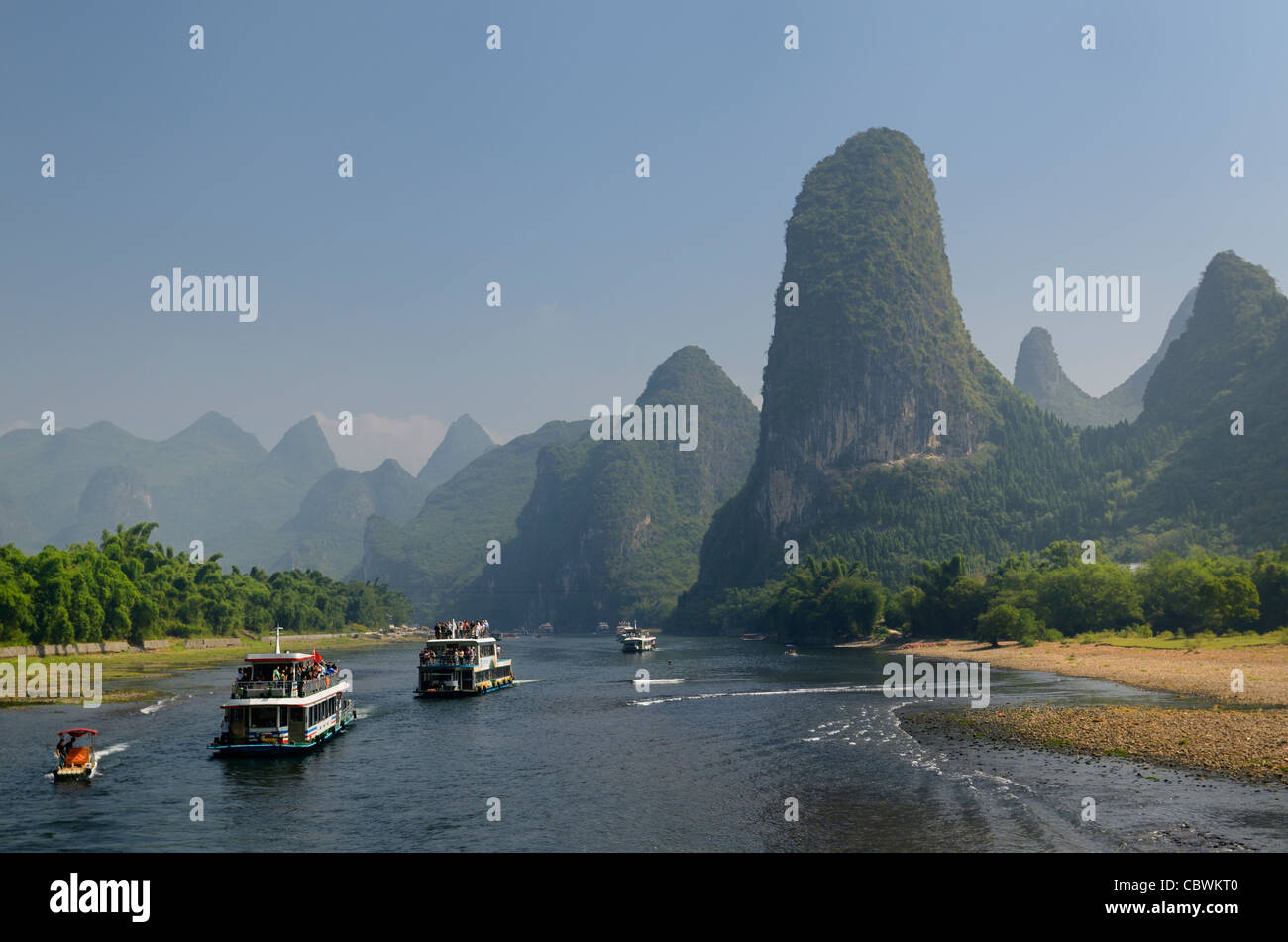 Tour boats traveling down the Li river Guangxi China with tall karst mountain cones Stock Photo