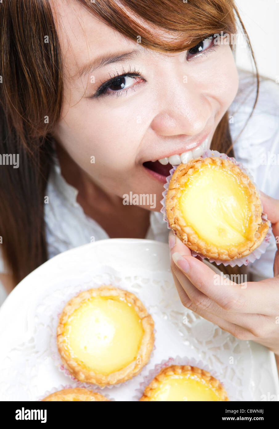 Close up young woman enjoying egg tart Stock Photo
