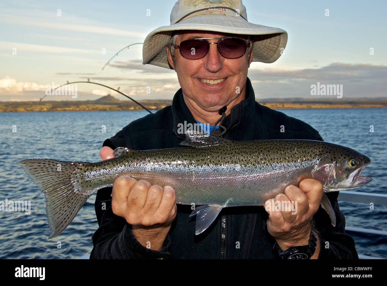 Happy make angler holding fat Great Lake Taupo rainbow trout in his hands Stock Photo