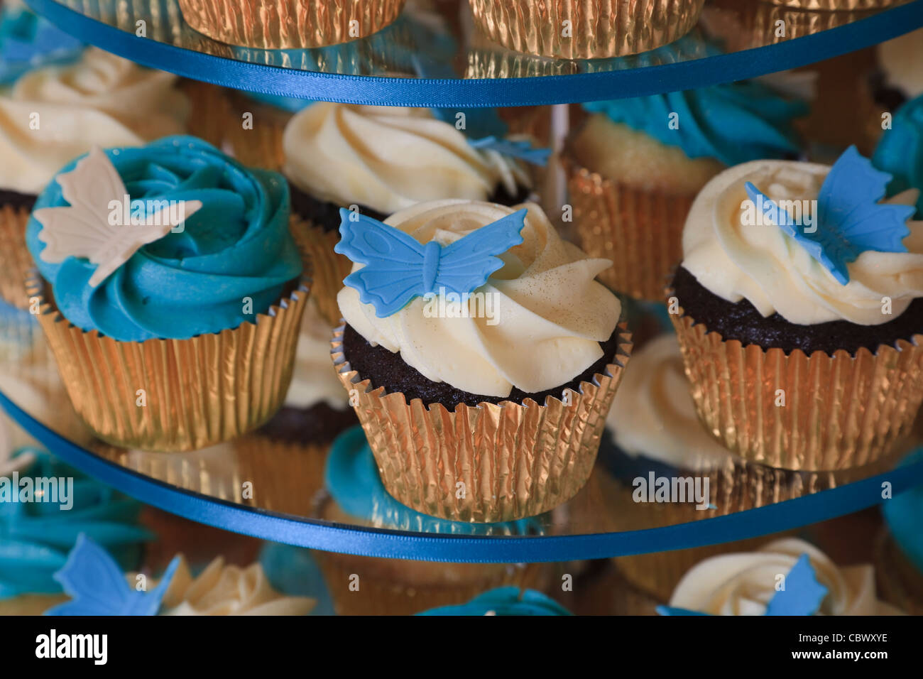 Small cakes with cream icing and butterfly styled decorations Stock