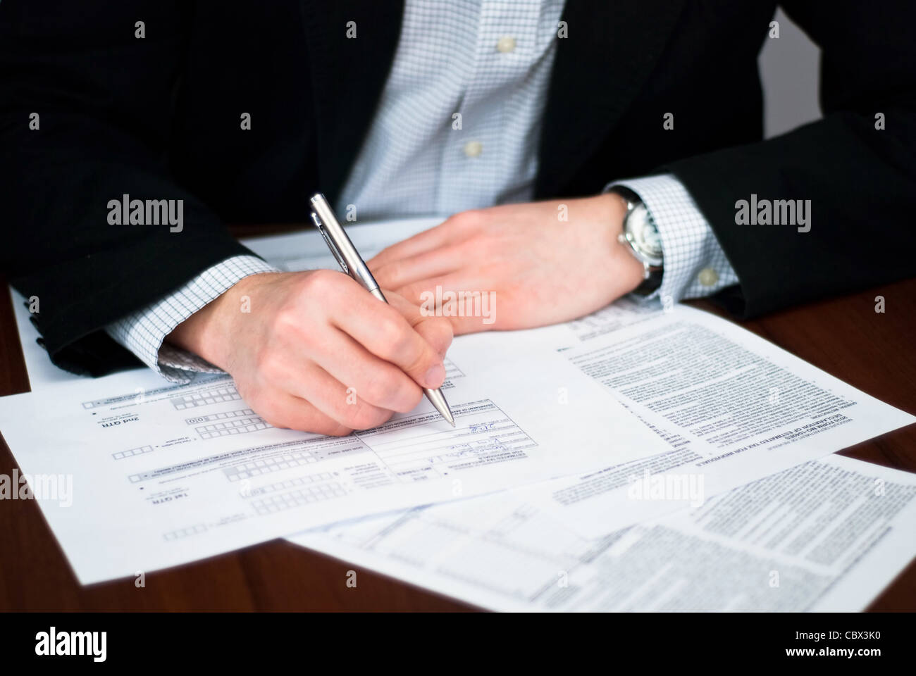 Filling out business documents on a desk Stock Photo - Alamy