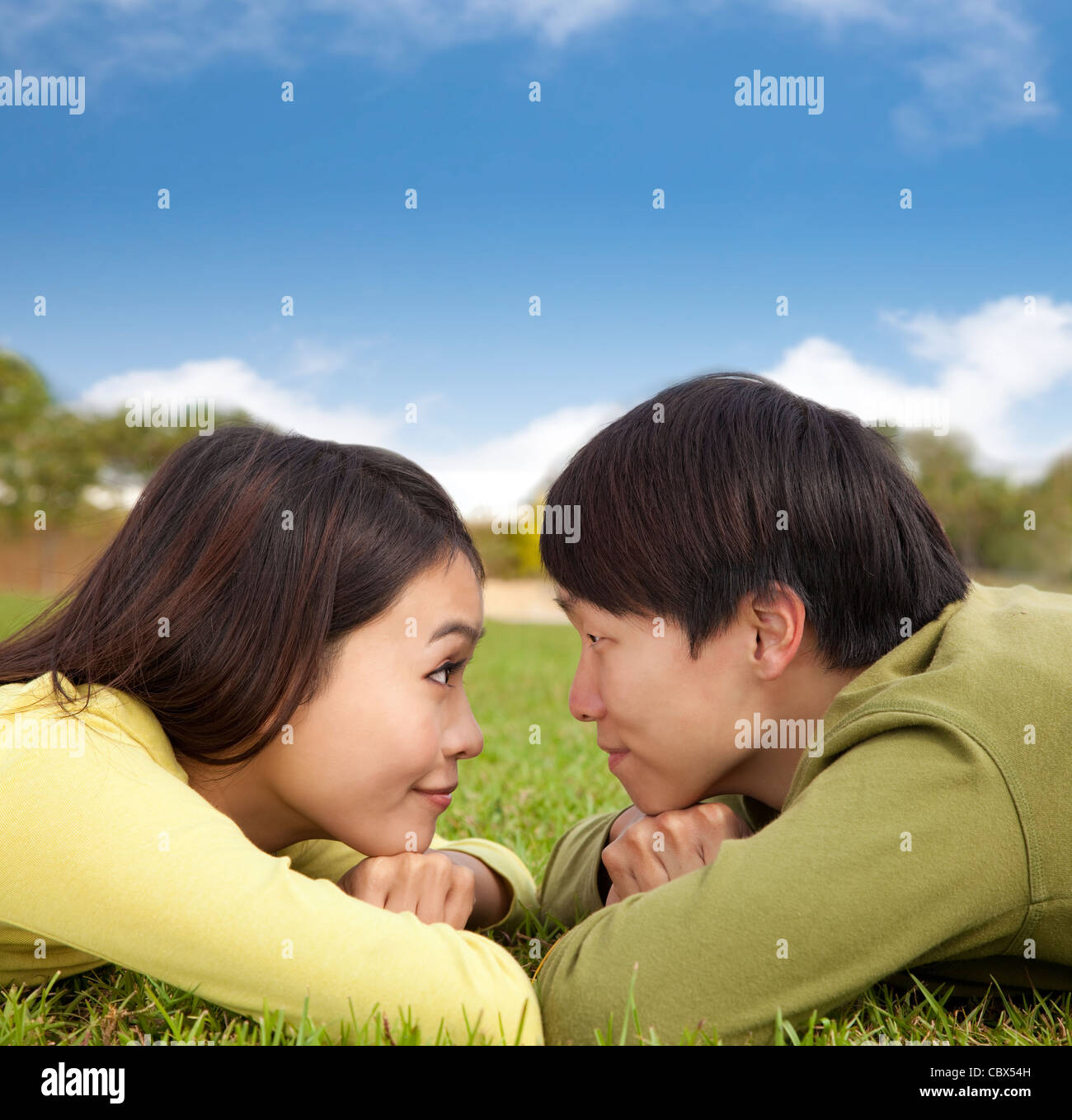 Happy asian couple lying on the grass with cloud background Stock Photo ...