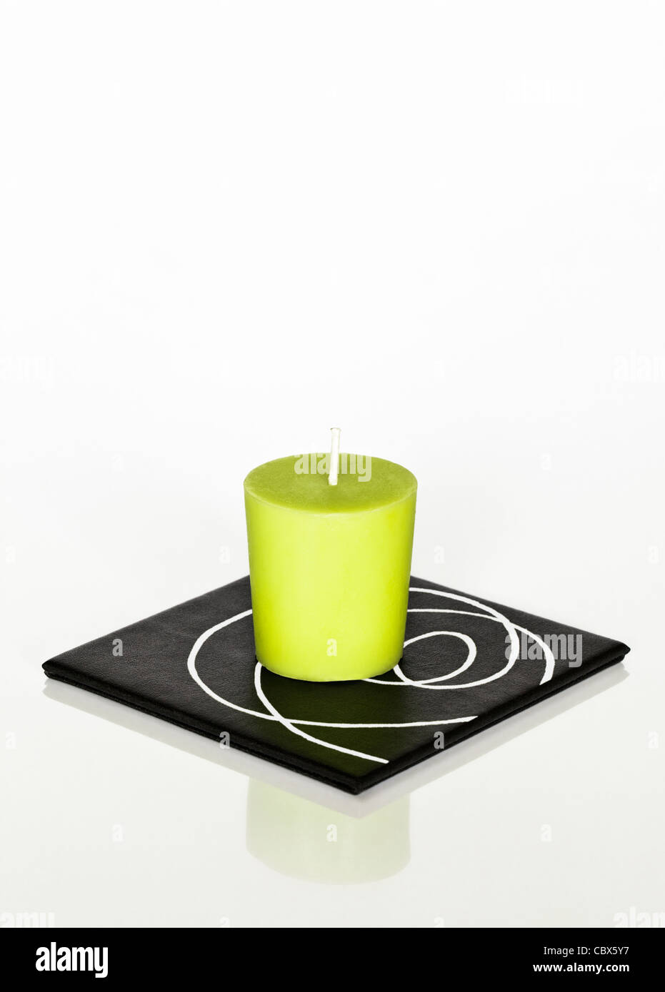 One green candle on square coaster Stock Photo