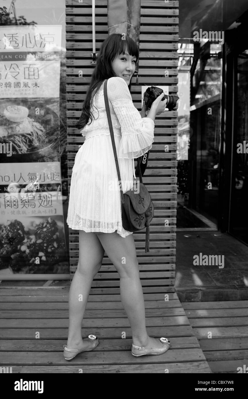 Beijing, Gulou. Young woman making photos on the street. Stock Photo