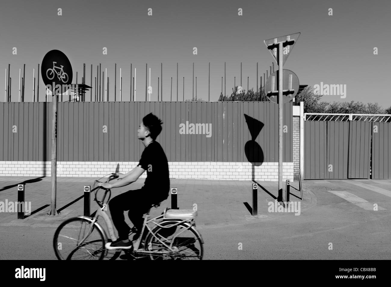 Beijing, Maizidian. Man on a bike passing a construction site. Stock Photo