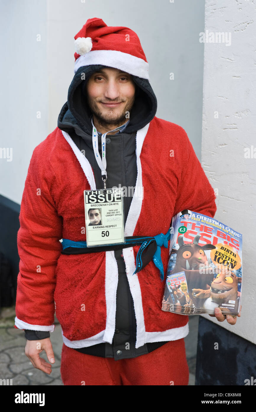 Big Issue seller in Father Christmas Xmas outfit in town centre of Hay-on-Wye Powys Wales UK Stock Photo